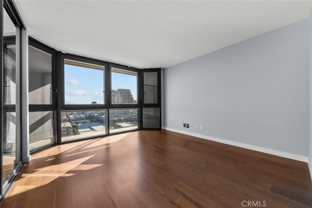 unfurnished room featuring a wall of windows and hardwood / wood-style floors