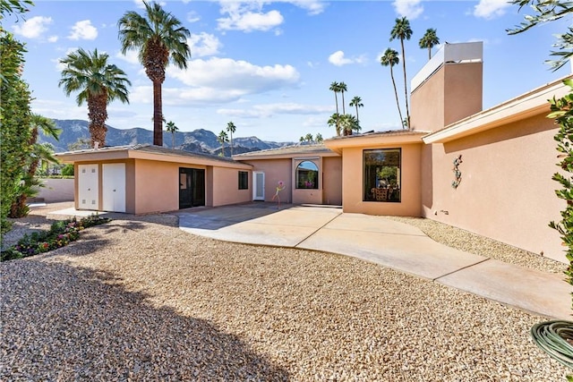 view of front of home featuring a patio area, stucco siding, and a mountain view