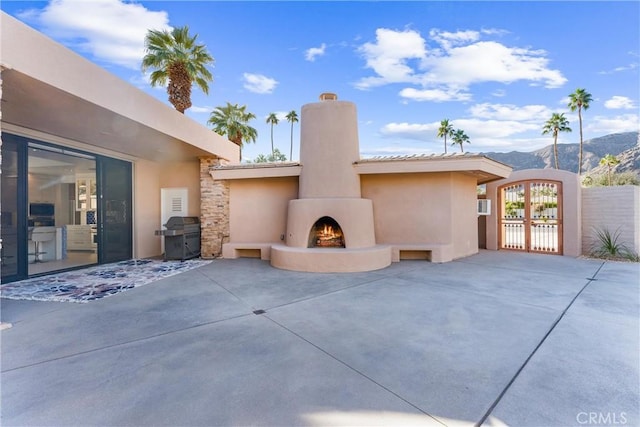 view of patio / terrace with a mountain view, a lit fireplace, area for grilling, and a gate