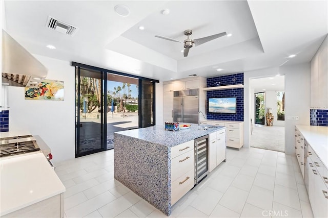 kitchen with a raised ceiling, wine cooler, visible vents, and stainless steel built in refrigerator