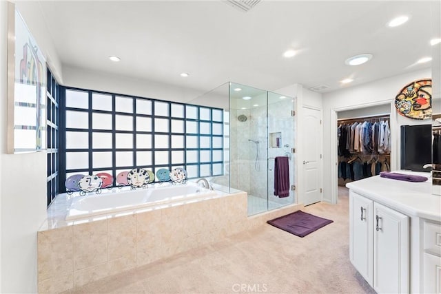 bathroom with vanity, recessed lighting, a stall shower, a spacious closet, and a garden tub