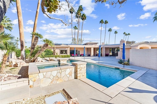 pool with an in ground hot tub and a patio