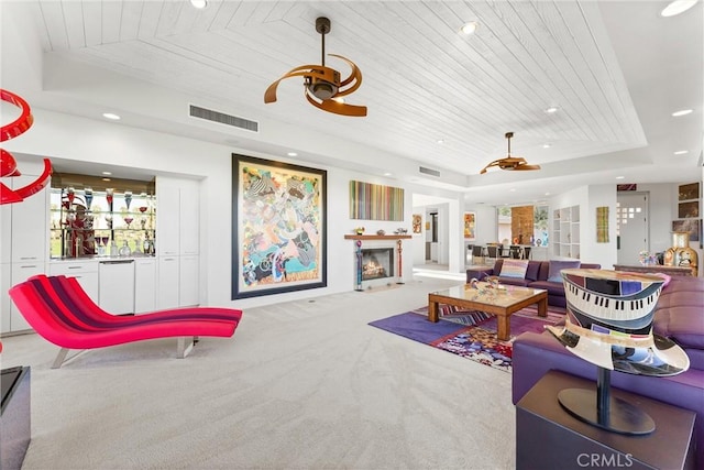 living room with carpet, visible vents, a warm lit fireplace, wood ceiling, and a raised ceiling