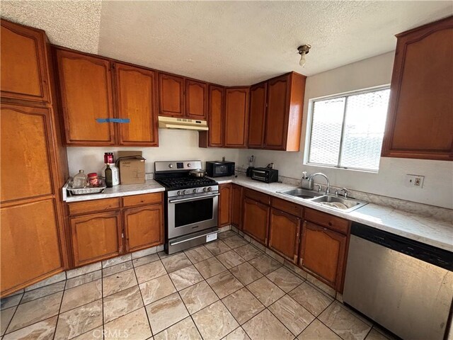 kitchen featuring stainless steel appliances, a textured ceiling, and sink