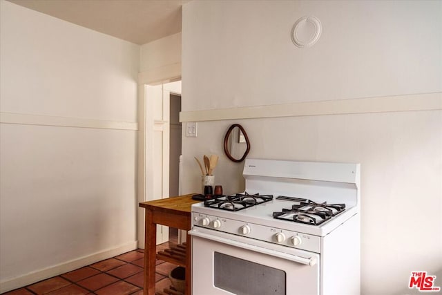 kitchen featuring white gas stove and dark tile patterned flooring