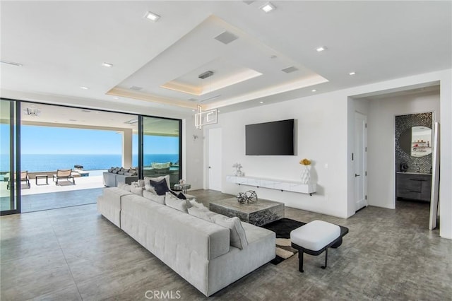 living room featuring expansive windows, a water view, and a raised ceiling