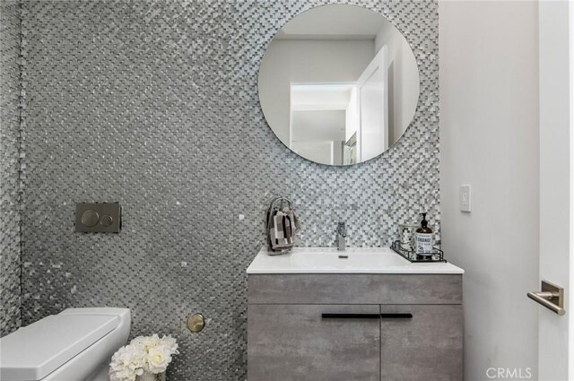 bathroom with backsplash, toilet, and vanity