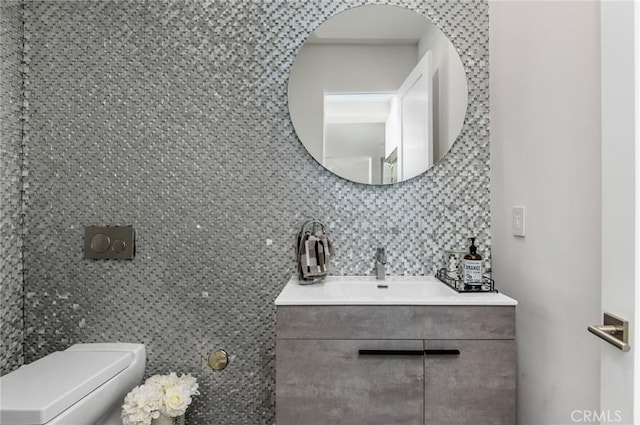 bathroom featuring toilet, tasteful backsplash, tile walls, and vanity