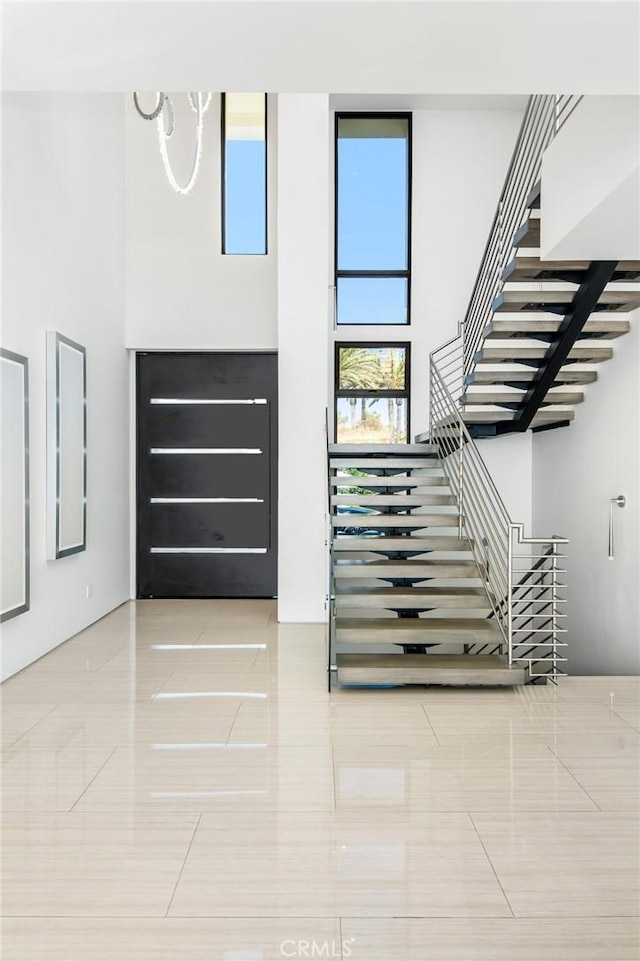 staircase featuring a towering ceiling and tile patterned floors