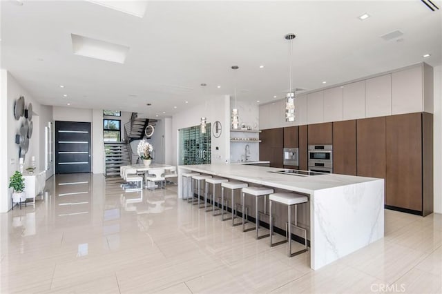 kitchen featuring modern cabinets, black electric cooktop, stainless steel double oven, a sink, and recessed lighting