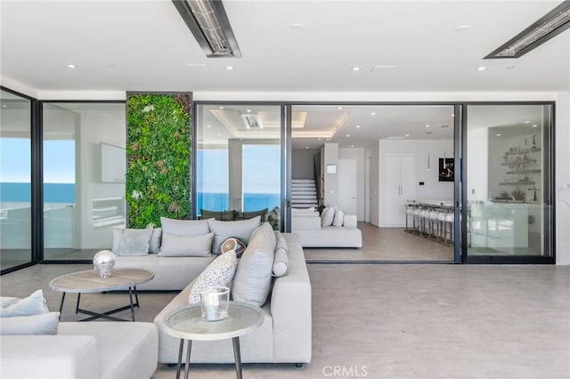 living room featuring expansive windows, a water view, and a healthy amount of sunlight