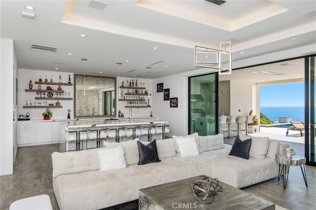 living area featuring visible vents, a raised ceiling, indoor wet bar, and recessed lighting