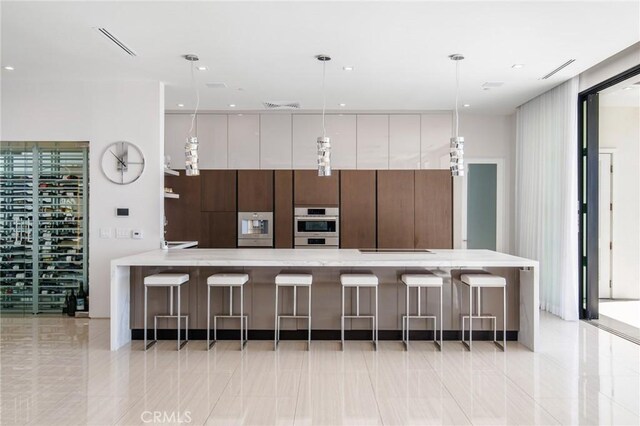 kitchen with pendant lighting, light tile patterned floors, light stone counters, a breakfast bar, and stainless steel double oven