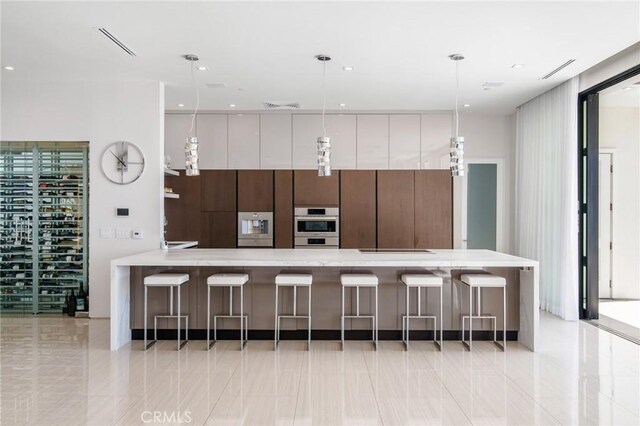 kitchen featuring stainless steel double oven, light countertops, a kitchen bar, and modern cabinets