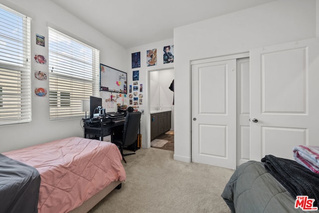 bedroom featuring connected bathroom, a closet, and light colored carpet