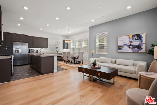 living room featuring light wood-type flooring, a chandelier, and sink