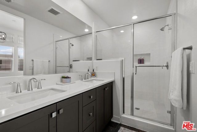 bathroom featuring a shower with shower door and vanity