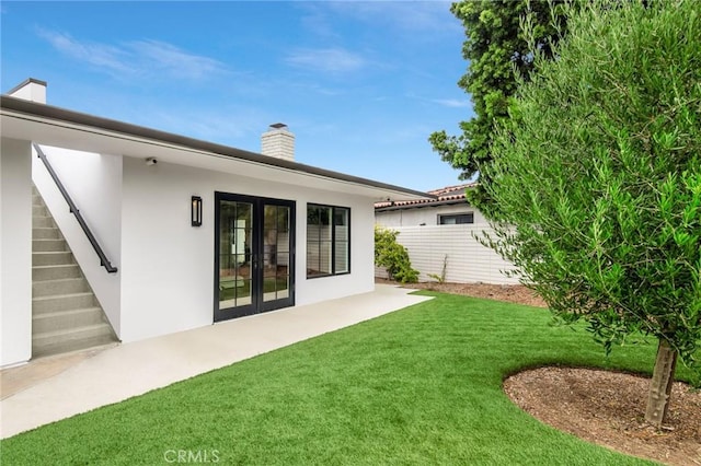 back of property with french doors, a lawn, and a patio