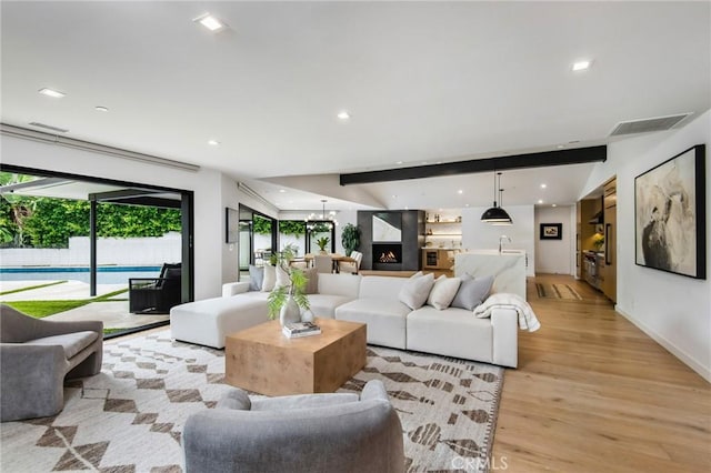 living room featuring a fireplace, light hardwood / wood-style floors, and beamed ceiling