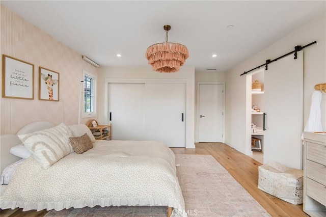 bedroom featuring a barn door and light hardwood / wood-style flooring