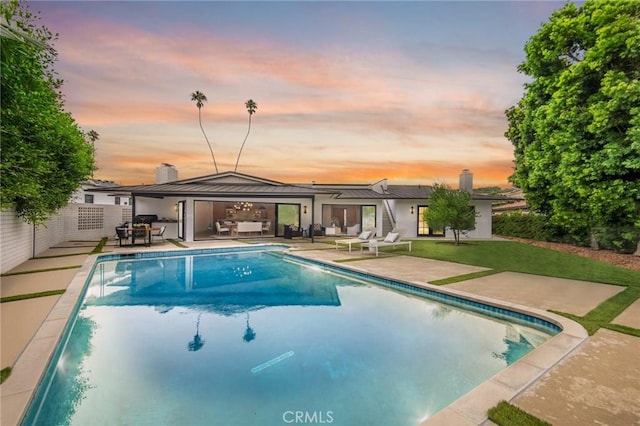 pool at dusk with a patio area