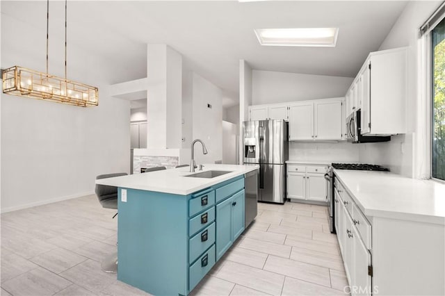 kitchen with pendant lighting, sink, appliances with stainless steel finishes, blue cabinetry, and white cabinets