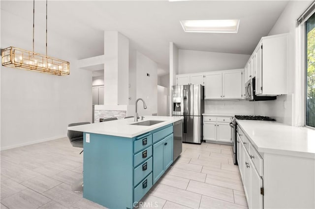 kitchen featuring appliances with stainless steel finishes, decorative light fixtures, blue cabinets, white cabinets, and sink