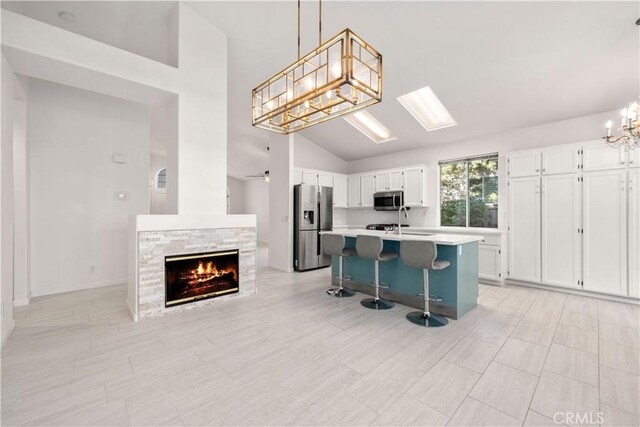 kitchen featuring decorative light fixtures, a kitchen breakfast bar, white cabinetry, and appliances with stainless steel finishes