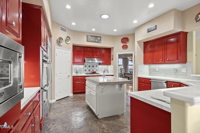 kitchen with appliances with stainless steel finishes, decorative backsplash, a kitchen island with sink, a kitchen breakfast bar, and sink