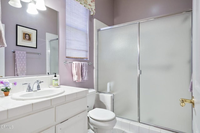 bathroom with toilet, vanity, and an enclosed shower