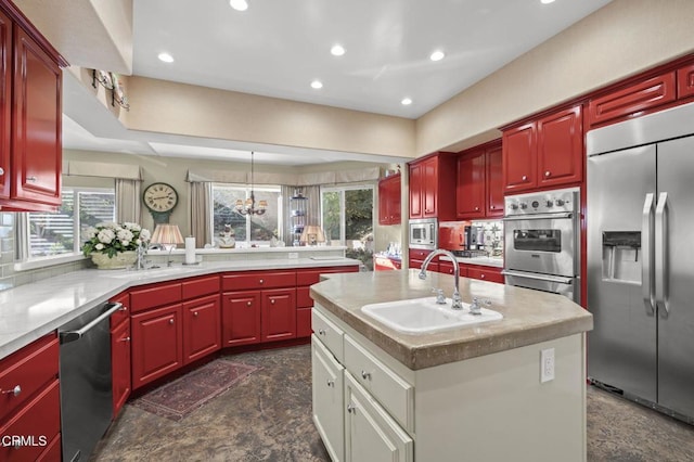 kitchen with sink, an inviting chandelier, an island with sink, and built in appliances