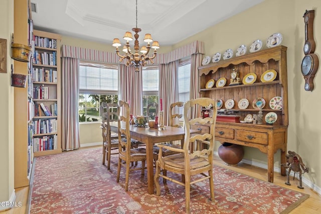 dining room with wood-type flooring, a tray ceiling, crown molding, and a chandelier