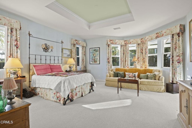 carpeted bedroom featuring ornamental molding, a tray ceiling, and multiple windows