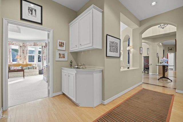 bar with white cabinetry and light hardwood / wood-style floors