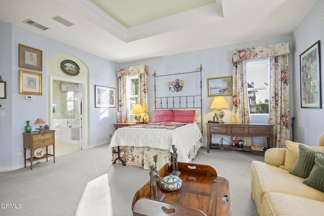 bedroom featuring a raised ceiling, light carpet, connected bathroom, and ornamental molding