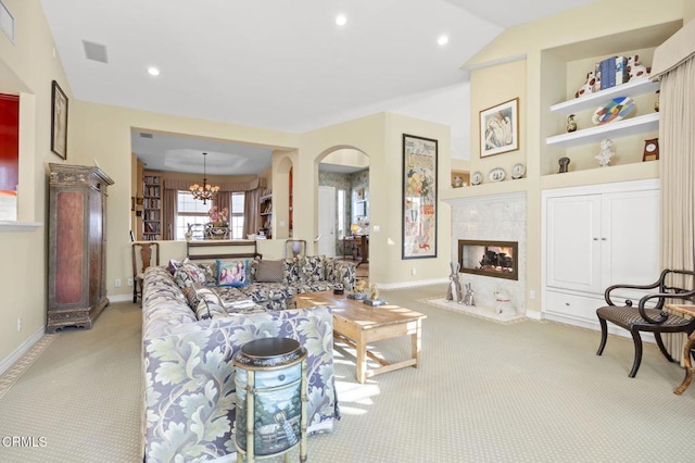 carpeted living room with a chandelier, a multi sided fireplace, and built in features