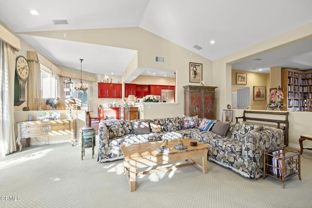 living room featuring vaulted ceiling, an inviting chandelier, and light colored carpet