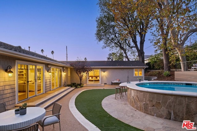 pool at dusk featuring a patio