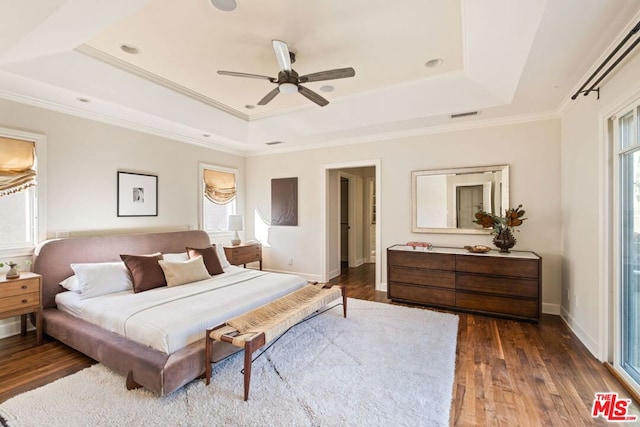 bedroom with dark wood-type flooring, ceiling fan, ornamental molding, and a raised ceiling