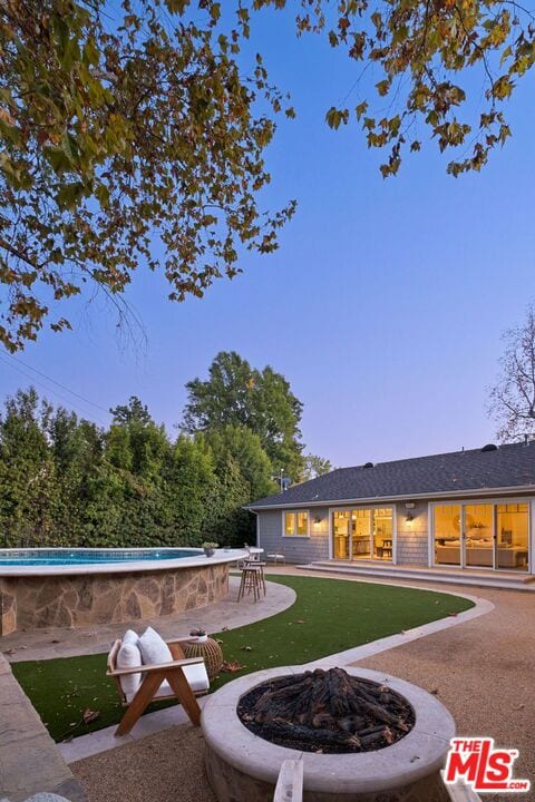 exterior space featuring an outdoor fire pit, a bar, and a patio