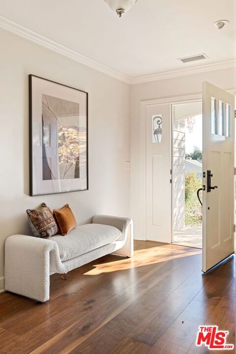 foyer entrance with dark wood-type flooring and crown molding