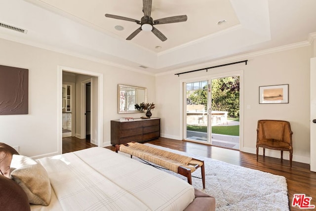 bedroom featuring ceiling fan, access to exterior, dark hardwood / wood-style floors, and a tray ceiling