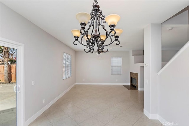 unfurnished dining area featuring a high end fireplace, a chandelier, and light tile patterned flooring