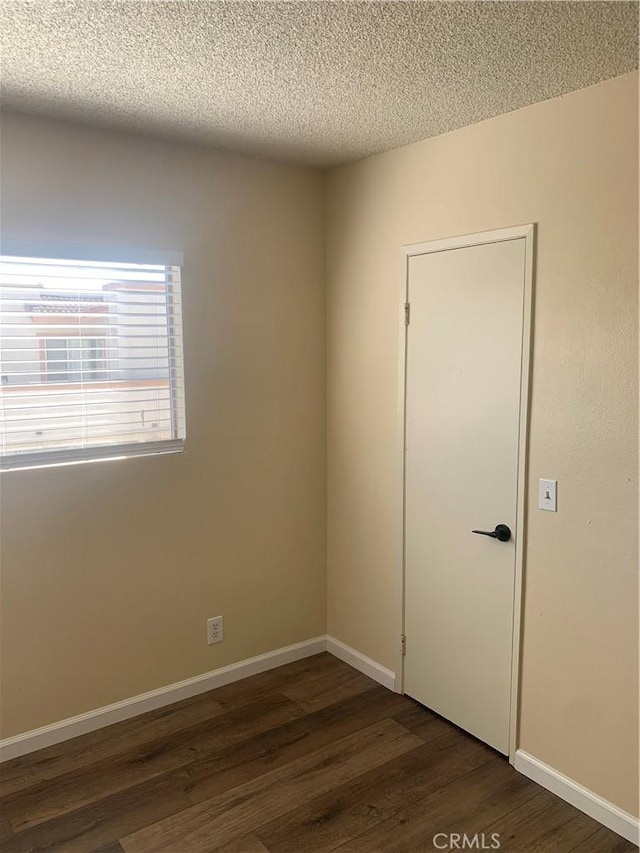 21834 Belshire Ave Unit 2, Hawaiian Gardens, CA 90716 - spare room with baseboards, dark wood-style flooring, and a textured ceiling