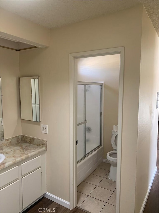 21834 Belshire Ave Unit 2, Hawaiian Gardens, CA 90716 - full bathroom featuring vanity, baseboards, enclosed tub / shower combo, tile patterned floors, and toilet