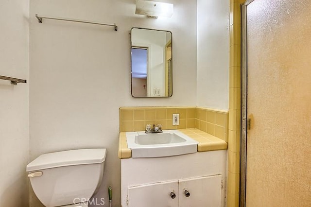 bathroom with vanity, backsplash, toilet, and a shower with shower door