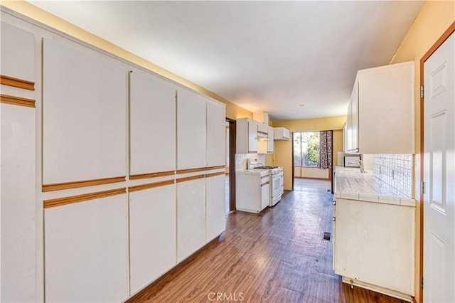 kitchen with white cabinets, tile counters, dark hardwood / wood-style floors, and white range with gas stovetop