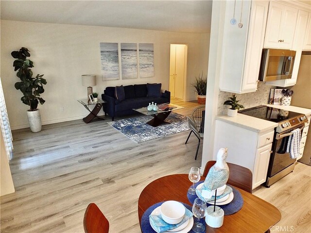 interior space with light hardwood / wood-style flooring, white cabinets, and range with electric cooktop