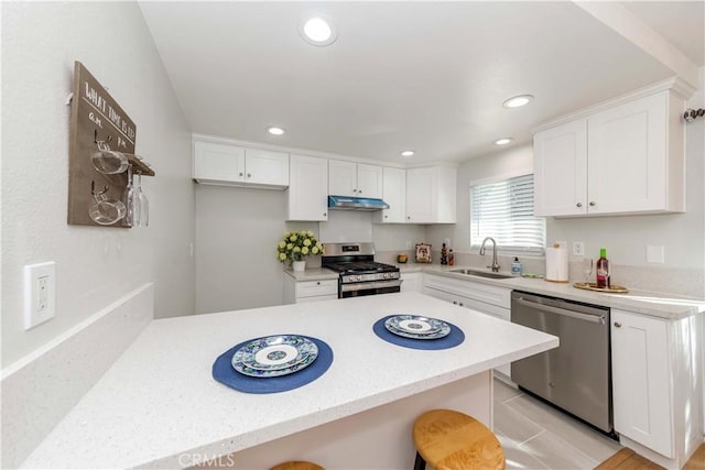 kitchen featuring stainless steel appliances, a kitchen bar, white cabinetry, and sink