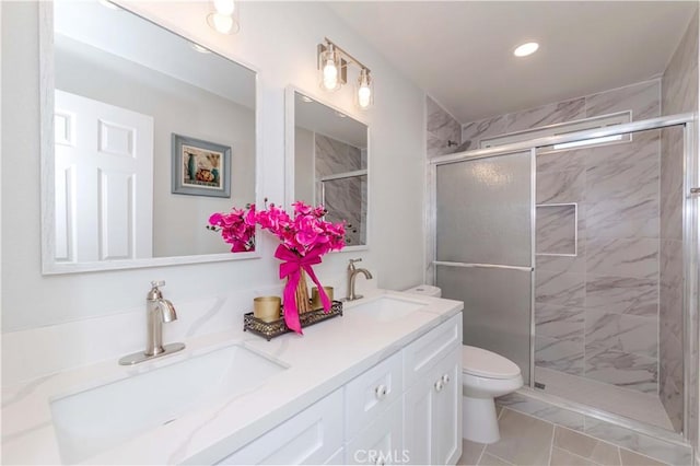 bathroom with toilet, vanity, and a shower with shower door